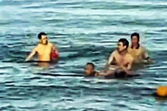 Hình ảnh Trung tá Bùi Văn Nhiên cùng người dân cứu cháu bé bị đuối nước. (Nguồn: qdnd.vn)