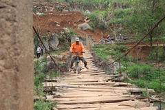 Người dân đi qua một cây cầu treo đã xuống cấp tại xã Chiềng Lương, huyện Mai Sơn. (Ảnh: Hữu Quyết/TTXVN)