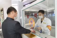 Khử khuẩn tay, đo thân nhiệt, nhằm ngăn chặn sự lây lan của dịch COVID-19 trước khi vào trung tâm thương mại ở Bình Nhưỡng, Triều Tiên. (Ảnh: AFP/TTXVN)