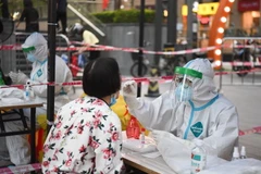 Nhân viên y tế lấy mẫu xét nghiệm COVID-19 cho người dân tại Quảng Châu, Trung Quốc. (Ảnh: AFP/TTXVN)