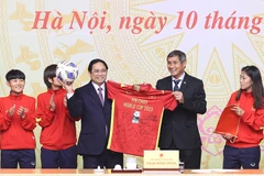Huấn luyện viên Mai Đức Chung và các cầu thủ đội tuyển nữ Việt Nam tặng quà lưu niệm cho Thủ tướng Phạm Minh Chính. (Ảnh: Dương Giang/TTXVN)