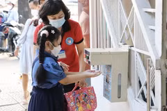 Giáo viên hướng dẫn học sinh rửa tay trước khi vào lớp. (Ảnh: Hồng Giang/TTXVN)