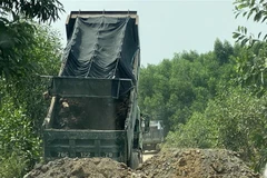 Một số đối tượng dùng xe tải chặn đầu, đổ đất bịt kín lối ra khỏi mỏ đất để uy hiếp phóng viên. (Ảnh: Lê Ngọc Phước/TTXVN)