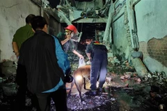 Lực lượng chức năng huy động chó nghiệp vụ tham gia tìm kiếm tung tích những người mắc kẹt trong vụ cháy nhà. (Ảnh: Nguyễn Thành/TTXVN)