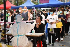 Nhân viên y tế lấy mẫu xét nghiệm COVID-19 cho người dân tại Quảng Châu, Trung Quốc. (Ảnh: AFP/TTXVN)