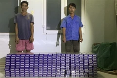 Đối tượng Nguyễn Văn Đoàn và Võ Thanh Thành bị Đồn Biên phòng Vàm Trảng Trâu bắt giữ khi vận chuyển 2.000 gói thuốc lá lậu. (Ảnh: TTXVN phát)