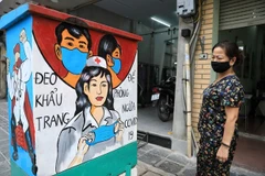 Người dân xem những bức tranh cổ động về công tác phòng chống dịch COVID-19. (Ảnh: Thành Đạt/TTXVN)
