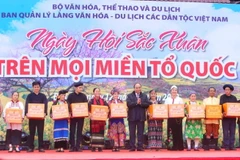 Chủ tịch nước Nguyễn Xuân Phúc tặng quà đồng bào dân tộc tại Làng Văn hóa-Du lịch các dân tộc Việt Nam. (Ảnh: Tuấn Đức/TTXVN)