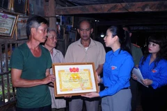 Đại diện gia đình anh Quàng Văn Xôm nhận Bằng khen từ Bí thư Tỉnh đoàn Sơn La Cầm Thị Huyền Trang. (Ảnh: Quang Quyết/TTXVN)