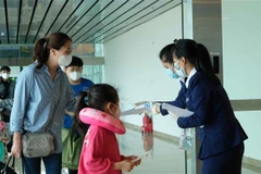 Nhân viên Sân bay quốc tế Cam Ranh phát tờ rơi hướng dẫn phòng dich COVID-19 cho hành khách tại khu vực nhập cảnh. (Ảnh: Nguyễn Dũng/TTXVN)