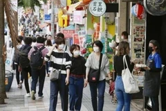 Người dân đeo khẩu trang phòng tránh dịch viêm đường hô hấp cấp COVID-19 khi đi dạo tại khu phố mua sắm ở Okinawa, miền Nam Nhật Bản. (Ảnh: Kyodo/TTXVN)