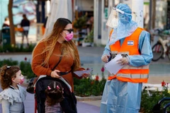 Nhân viên y tế hướng dẫn người dân tới trung tâm xét nghiệm COVID-19 tại thành phố Netanya (Israel). (Ảnh: AFP/TTXVN)