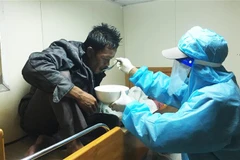 Thuyền viên tàu Kiểm ngư KN 464 chăm sóc sức khỏe cho ngư dân Benjamin Abdulla, sau khi ngư dân này được cứu vớt lên tàu. (Ảnh: TTXVN)