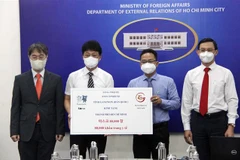 Ông Phạm Minh Tuấn, Phó Chủ tịch Ủy ban Mặt trận Tổ quốc Việt Nam Thành phố (thứ hai từ phải sang) tiếp nhận tượng trưng số khẩu trang do tỉnh Gangwon (Hàn Quốc) trao tặng. (Ảnh: Xuân Khu/TTXVN)