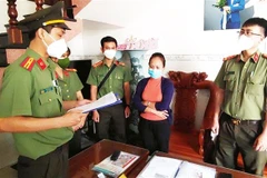 Cơ quan An ninh điều tra Công an tỉnh Bình Định đọc quyết định khởi tố và khám xét nhà ở của một bị can liên quan đến vụ án. (Ảnh: TTXVN)
