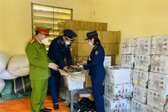 Lực lượng công an và quản lý thị trường kiểm đếm hàng lậu thu giữ. (Ảnh: TTXVN)