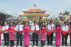 Các lãnh đạo tỉnh, địa phương và đại biểu cắt băng khánh thành Di tích khu mộ tập thể Liệt sỹ thuộc Sư đoàn 3 Sao vàng. (Ảnh: Viết Ý/TTXVN)