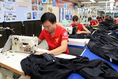 Dây chuyền may quần áo xuất khẩu. (Ảnh: Trần Việt/TTXVN)