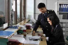 Làm thủ tục hải quan cho các đơn vị, doanh nghiệp tại cửa khẩu Lao Bảo. (Ảnh: Anh Tôn/TTXVN)