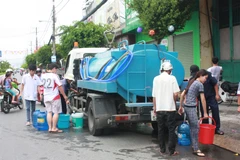 Người dân Rạch Giá phải sử dụng mọi vật dụng hiện có để lấy nước tại các xe bồn cấp nước. (Ảnh: Trường Giang/TTXVN)
