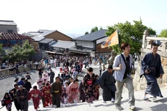 Hướng dẫn viên du lịch cầm cờ dẫn đầu đoàn du khách Trung Quốc mặc kimono thăm đền Kiyomizu-dera ở Kyodo. (Nguồn: Bloomberg)