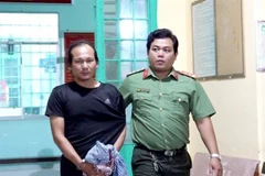 Lực lượng Công an bắt, áp giải Nguyễn Hoàng Nam về nơi giam giữ. (Ảnh: TTXVN phát)