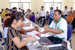 Người dân xã Nam Sơn (Sóc Sơn) nhận tiền đền bù hỗ trợ giải phóng mặt bằng vùng ảnh hưởng bán kính 500 mét của bãi rác Nam Sơn. (Ảnh: Mạnh Khánh/TTXVN)