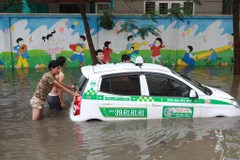 Chiếc xe taxi Thành Lợi nổi lềnh bềnh trong biển nước. (Ảnh: Minh Sơn/Vietnam+)