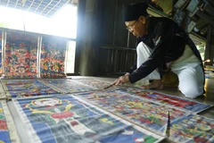 Ông Thanh thường xuyên phải kiểm tra, bảo quản những bức tranh thờ cổ của người Dao. (Ảnh: Nam Sương/TTXVN)