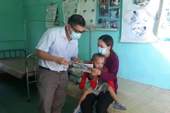 Cán bộ y tế địa phương phát tờ rơi tuyên truyền về bệnh bạch hầu để người dân phòng tránh. (Ảnh: Hồ Cầu/TTXVN)