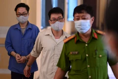 Bị cáo Lâm Hoàng Tùng (áo xanh), bị cáo Nguyễn Hải Nam (áo trắng) sau phiên tòa ngày 30/12/2020. (Ảnh: TTXVN phát)
