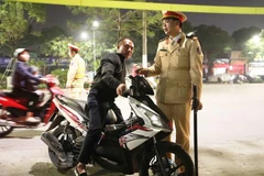 Một trường hợp không đội mũ bảo hiểm khi đi xe máy bị cảnh sát yêu cầu dừng xe để xử lý vi phạm. (Ảnh: Doãn Tấn/TTXVN)