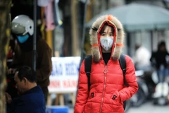 Người dân ra đường mặc áo ấm kín mít, đeo khẩu trang để chống lại giá rét. (Ảnh: Thành Đạt/TTXVN)