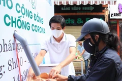 Người dân nhận gạo tại “ATM gạo nghĩa tình”. (Ảnh: Tuấn Anh/TTXVN)