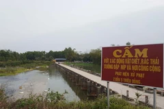 Mặc dù có biển cấm nhưng xác gia cầm, rác thải vẫn được xả bừa bãi ra đập. (Ảnh: Quân Trang-TTXVN)