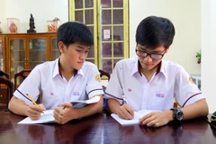 Hai anh em Tống Phước Thanh Bình và Tống Phước Thanh An (người đeo kính) trao đổi bài trước giờ lên lớp. (Ảnh: Tường Vi/TTXVN)