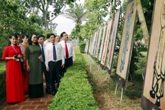 Lãnh đạo tỉnh Hà Tĩnh và du khách xem tranh tại Triển lãm. (Ảnh: Công Tường/TTXVN)