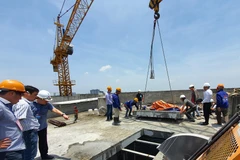 Lực lượng cưỡng chế cắt sàn mái tầng 18 công trình 8B Lê Trực, Hà Nội. (Ảnh: Mạnh Khánh/TTXVN)