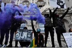 Người biểu tình giơ cao khấu hiệu và pháo sáng tại Quảng trường Nghị viện London trong một cuộc biểu tình chống phân biệt chủng tộc sáng 7/6.(Nguồn: Reuters)