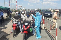 Nhân viên y tế đo thân nhiệt người ra vào thành phố Hồ Chí Minh tại chốt kiểm dịch. (Ảnh: Đinh Hằng/TTXVN)