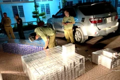 Lực lượng chức năng kiểm tra và tạm giữ số thuốc lá điếu nhập lậu. (Ảnh: Lê Thúy Hằng/TTXVN)