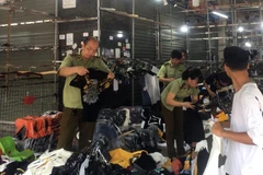 Lực lượng chức năng kiểm tra một cửa hàng kinh doanh quần áo tại chợ Ninh Hiệp. (Ảnh: TTXVN phát)