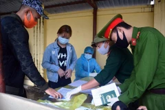 Các công dân ký giấy chứng nhận hoàn thành thời gian cách ly. (Ảnh: Phan Tuấn Anh/TTXVN)