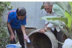 Người dân thau rửa các dụng cụ chứa nước để diệt bọ gậy. (Ảnh: Xuân Triệu/TTXVN)