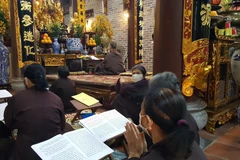 Phật tử hành lễ nhưng vẫn thực hiện nghiêm đeo khẩu trang phòng chống dịch. (Ảnh: Đinh Thuận/TTXVN)