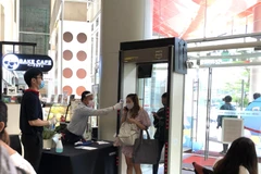Nhân viên của một trung tâm thương mại ở thủ đô Bangkok kiểm tra thân nhiệt của người vào tòa nhà. (Ảnh: Ngọc Quang/TTXVN)