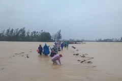 Người dân cố di chuyển trên một đoạn đường ngập nước do mưa lũ. (Nguồn: tuoitre.vn)