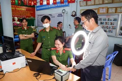 Cán bộ Công an phường Tân An, quận Ninh Kiều hướng dẫn người dân thực hiện đăng ký tài khoản định danh điện tử mức độ 2. (Ảnh: TTXVN phát)
