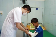 Bác sỹ Bệnh viện Đa khoa tỉnh Lai Châu kiểm tra vết thương cho cháu Hạng A Chù, xã Tả Lèng, huyện Tam Đường do đắp lá cây rừng gây phỏng cánh tay trái. (Ảnh: Đinh Thùy/TTXVN)