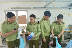 Lực lượng Quản lý thị trường kiểm tra cơ sở sản xuất khẩu trang. (Ảnh: PV/Vietnam+)